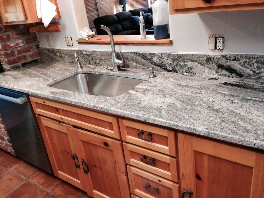 Kitchen with wooden cabinets, granite countertop, stainless steel sink, and a faucet.
