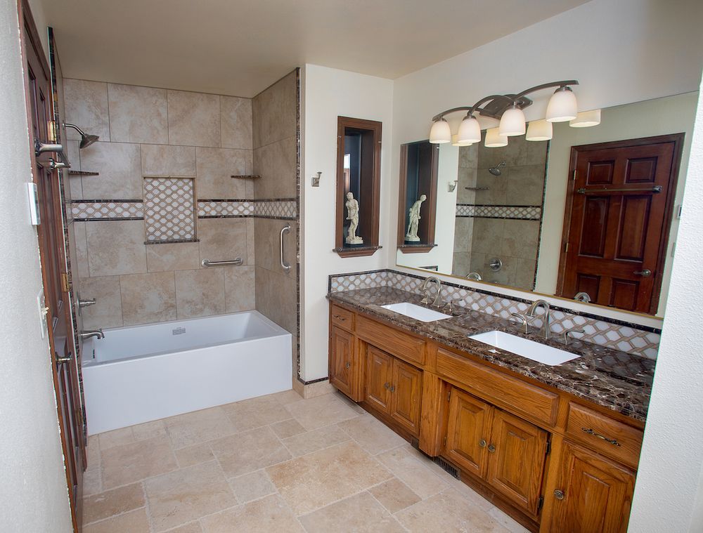 Bathroom with a tub and double vanity. Beige tile, dark wood cabinets, and granite countertops.