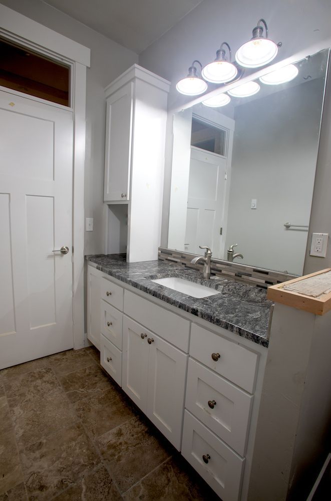 Bathroom with white cabinetry, granite countertop, and large mirror.