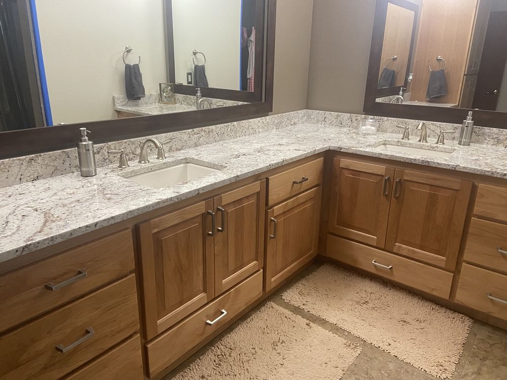 Bathroom with light wood cabinets, light granite countertops, and two sinks with mirrors.