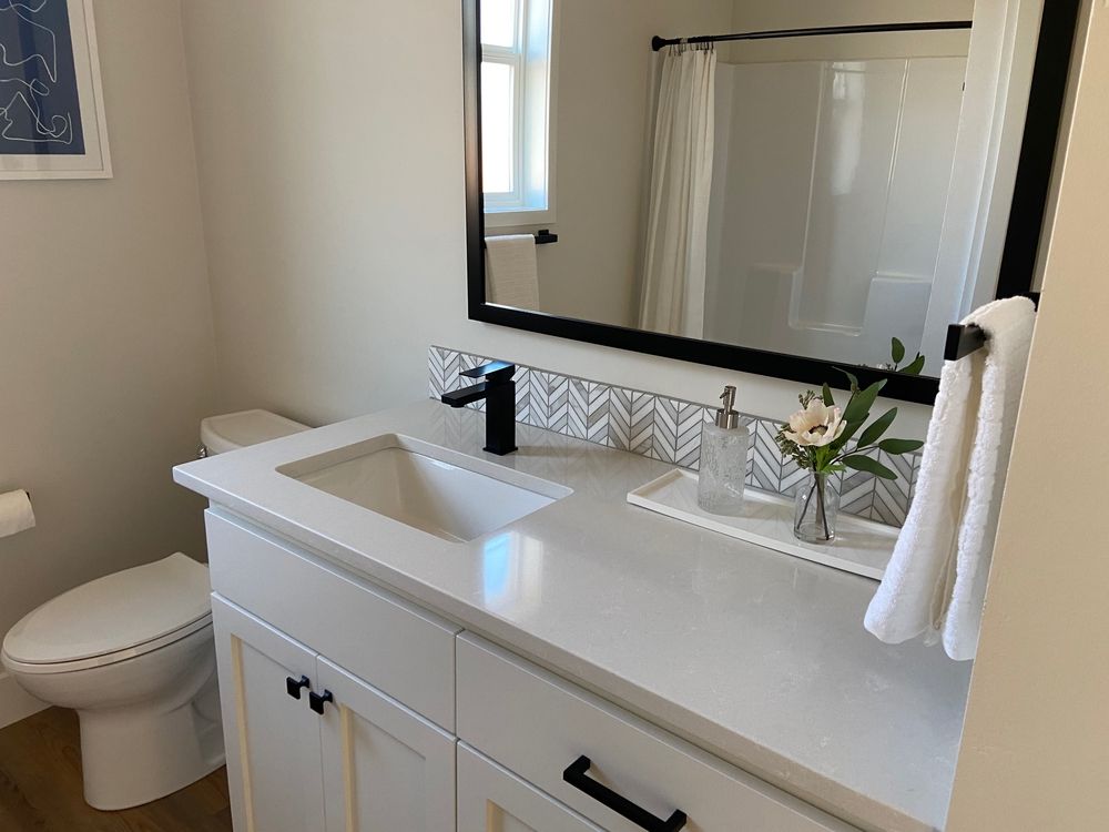 Bathroom with white vanity, black faucet, mirror, and toilet.