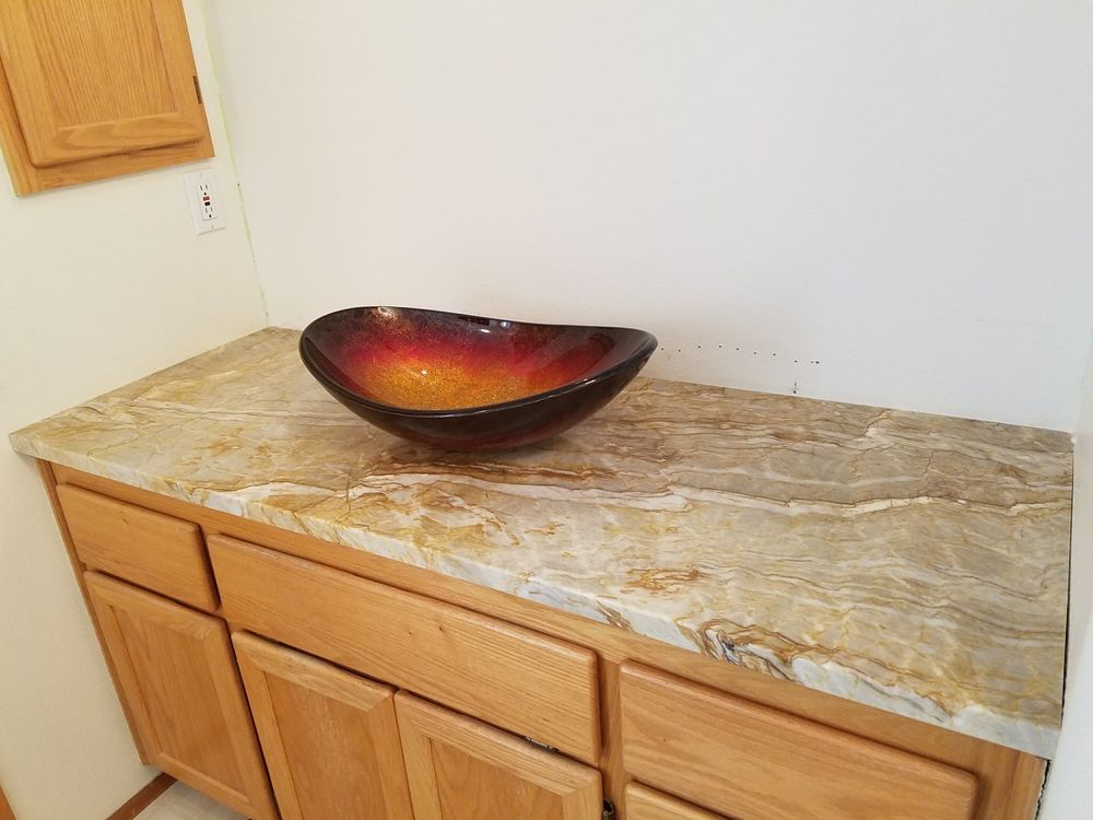 Bathroom vanity with a vessel sink on a marble countertop; wooden cabinets.