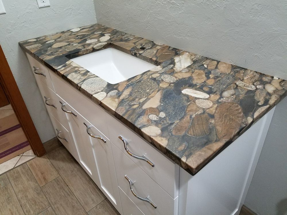 White bathroom vanity with patterned granite countertop and a white rectangular sink.
