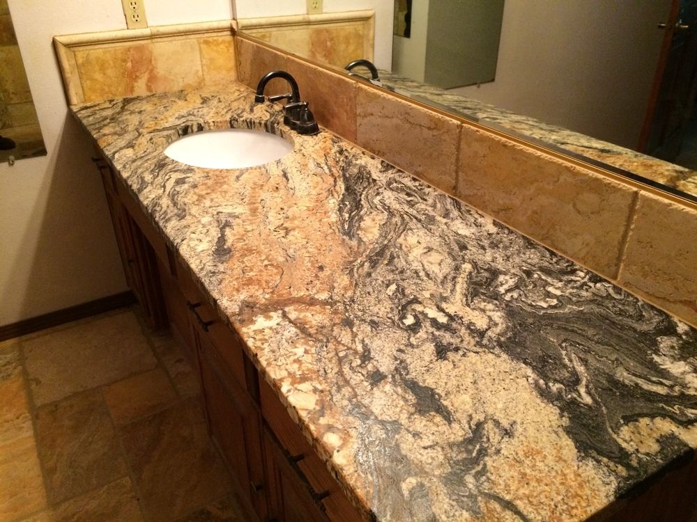 Bathroom with a granite countertop, oval sink, wooden cabinets, and large mirror.