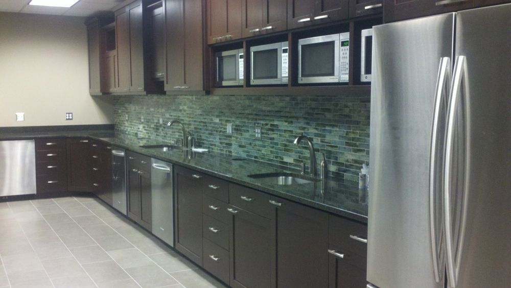 Kitchen with dark cabinets, stainless steel appliances, and a green tile backsplash.
