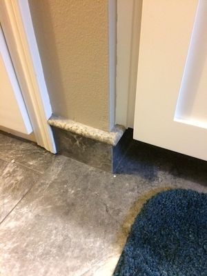 Doorway with gray tile flooring, baseboard, and white door.