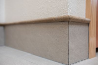 Tan baseboard with rounded top and corner next to a wall.
