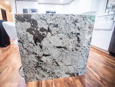 Granite kitchen island with white, black, and gray swirls on a hardwood floor.