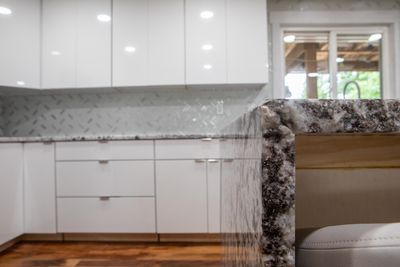 White kitchen with granite countertops and cabinets, a window, and hardwood floors.