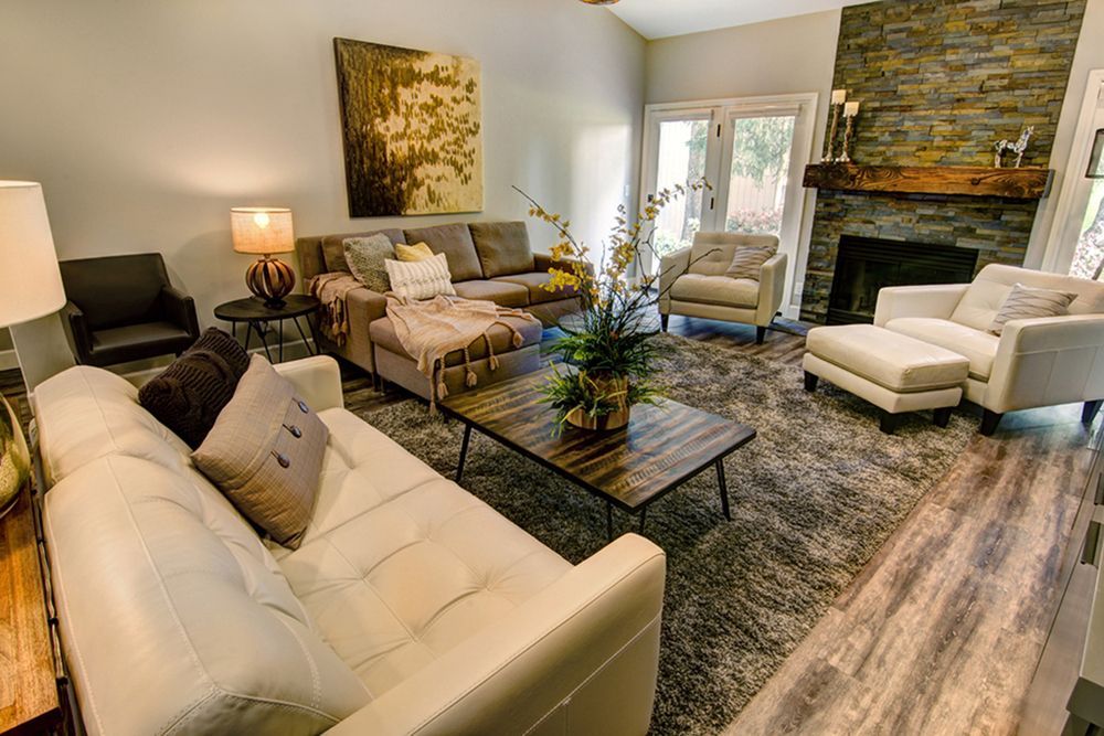 Living room with gray rug, couches, stone fireplace, and French doors.