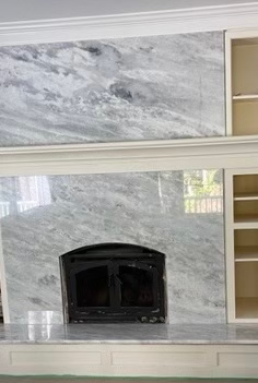 Fireplace with marble surround and built-in shelving, white trim, and a black firebox.