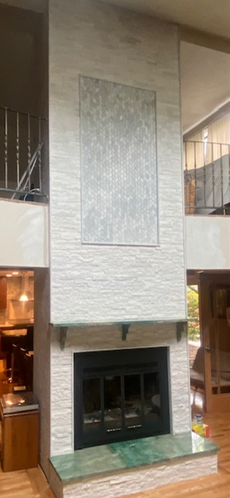 Tall fireplace with light gray textured stone, a dark firebox, and a green marble hearth.