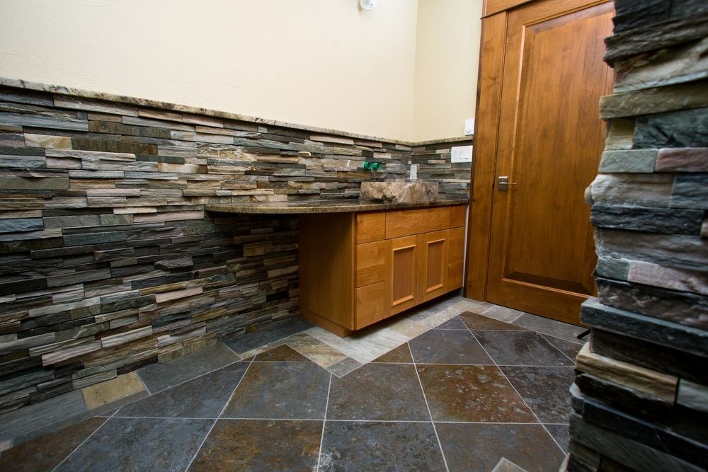 Stone-walled powder room with wooden vanity and matching door; slate tile floor.