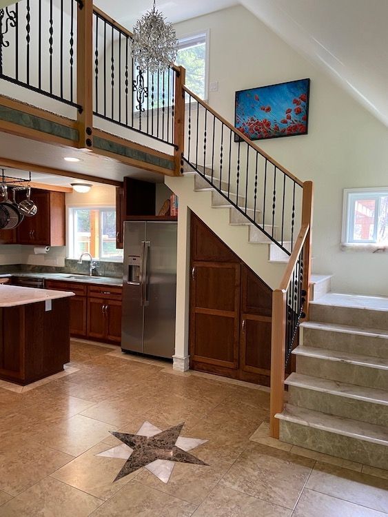 Kitchen with a staircase, stainless steel appliances, and a mosaic star on the floor.