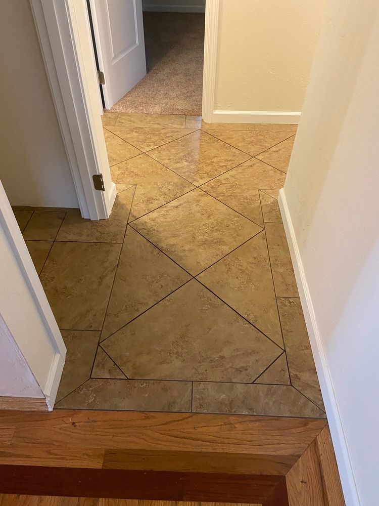 Entryway with patterned tile floor, wooden border, and carpeted hallway.