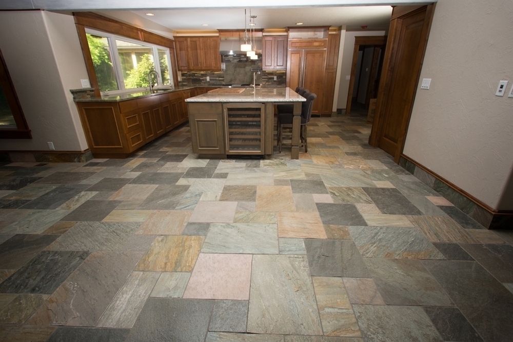 Kitchen with multi-colored slate tile flooring, wooden cabinets, and an island with a wine cooler.