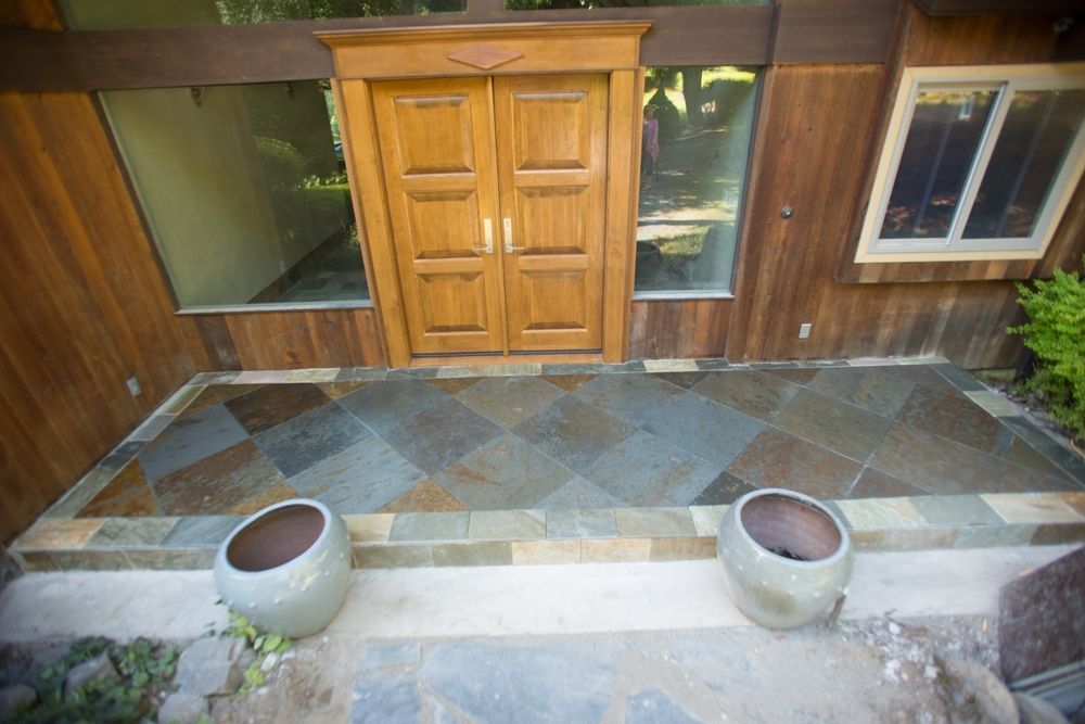 Wooden double doors and slate patio with potted plants.