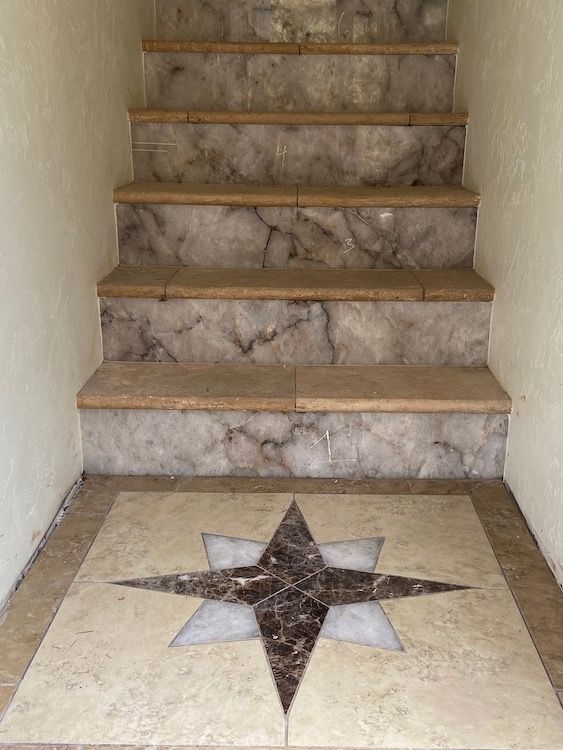 Staircase with marble steps and a decorative starburst tile on the landing.