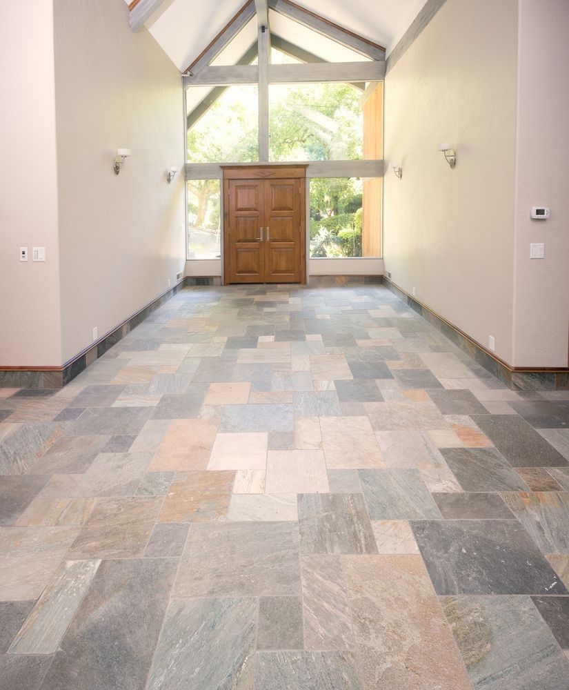 Spacious entryway with stone tile floor, wooden door, large window, and neutral walls.