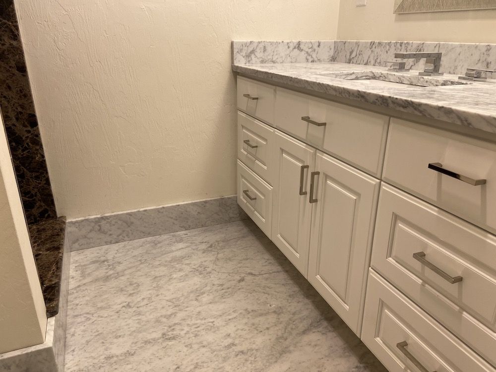 White bathroom vanity with marble countertop and gray floor tile.
