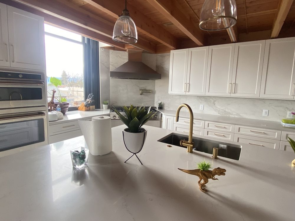 Modern kitchen with white cabinets, gold fixtures, and a large island.