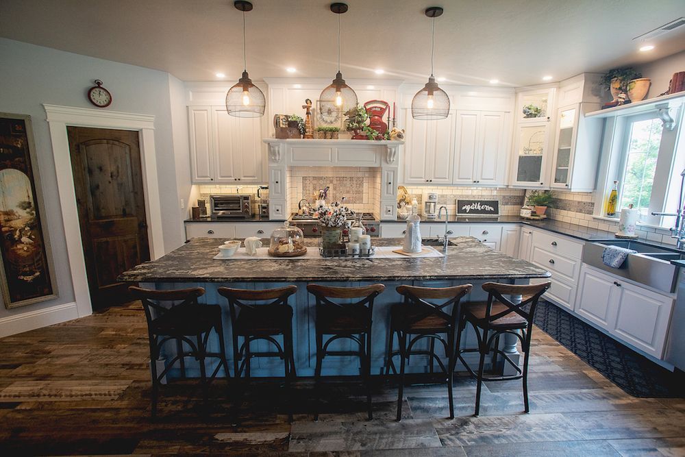 Rustic kitchen with large island, white cabinets, and pendant lights.