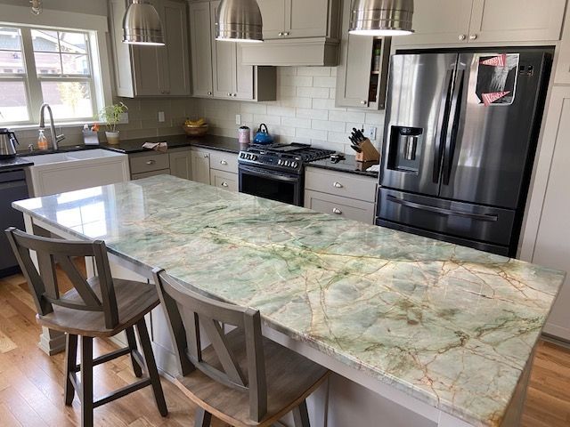 Kitchen with a green-veined granite island, light gray cabinets, and stainless steel appliances.