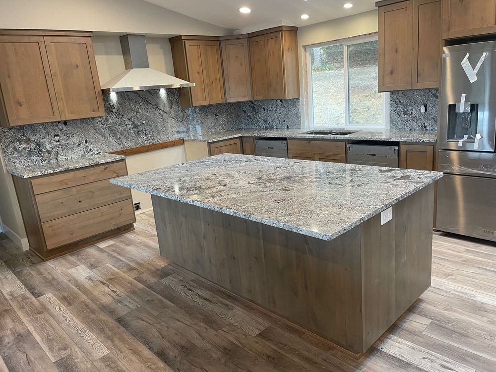 Kitchen with light wood cabinets, granite countertops, stainless steel appliances, and a central island.