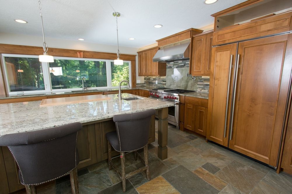 Kitchen with wood cabinets, island with seating, granite countertops, and stainless steel appliances.
