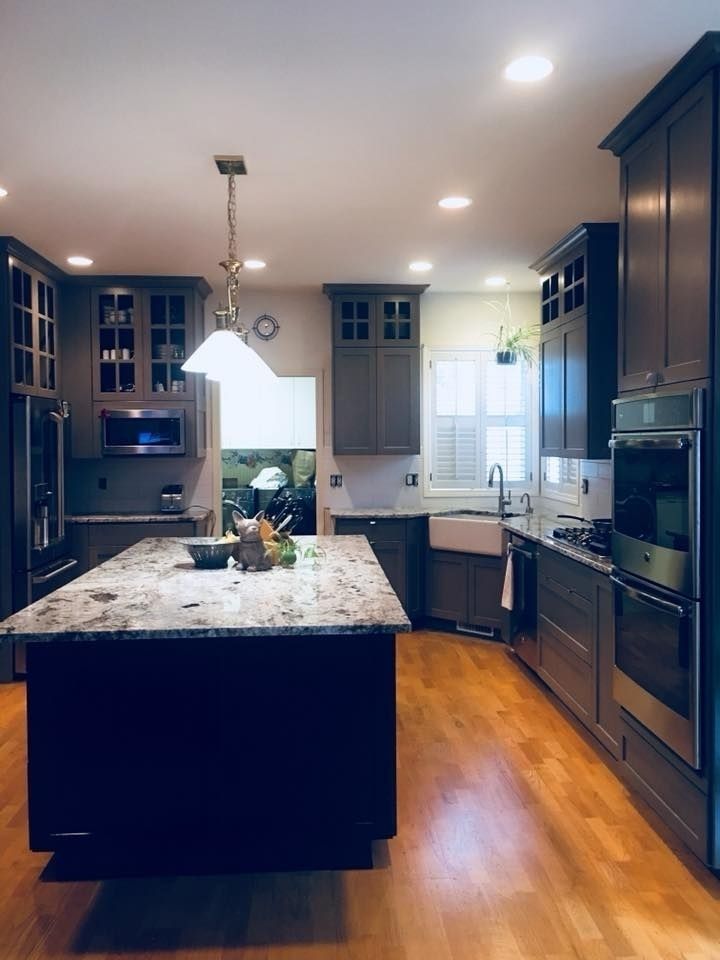 Modern kitchen with gray cabinets, granite countertops, island, and wood floors.