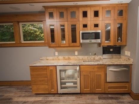 Kitchenette with wooden cabinets, granite countertop, stainless steel appliances, and a window.