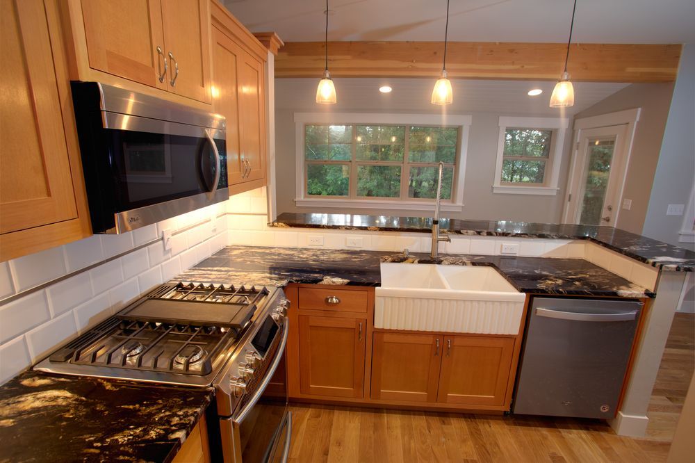 Kitchen with wooden cabinets, stainless steel appliances, granite countertops, and a farmhouse sink.