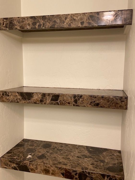 Three marble-look floating shelves installed on a white wall.