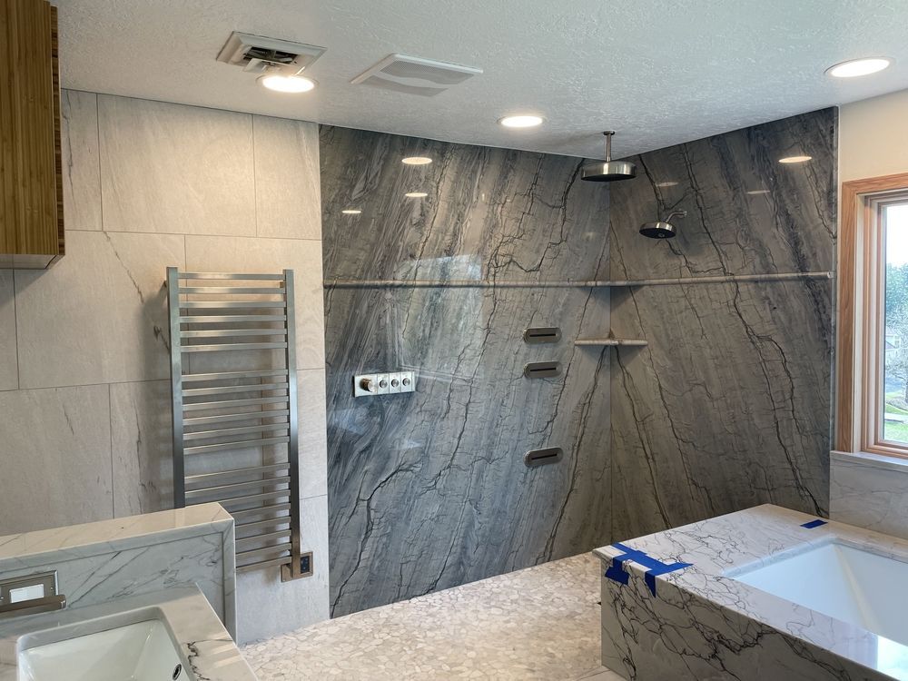 Modern bathroom with gray and white tile, shower, towel warmer, and tub.