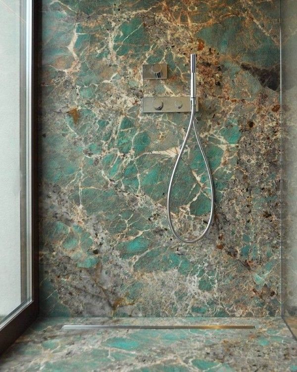 Shower with green marble walls and a stainless steel shower head.