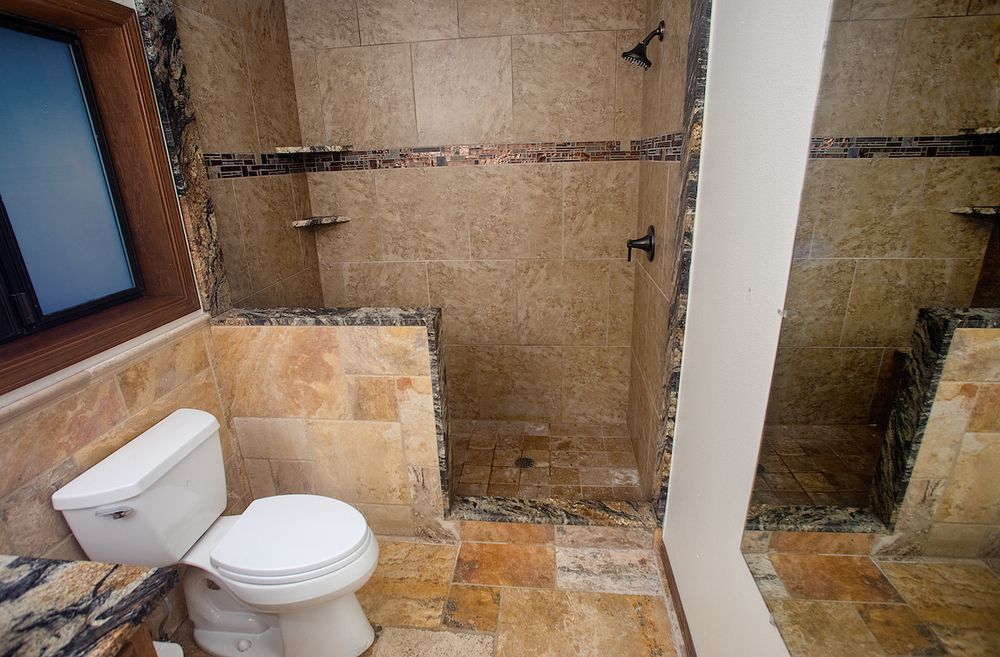 Bathroom with tan tile, shower, and toilet; a window is visible.