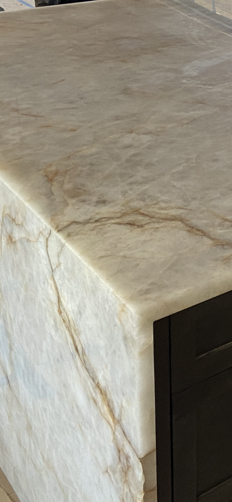 Close-up view of a countertop with a marbled appearance and dark cabinetry.