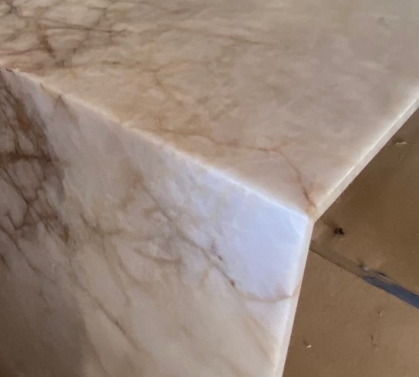Close-up of a marble countertop's corner, featuring beige and brown veining.