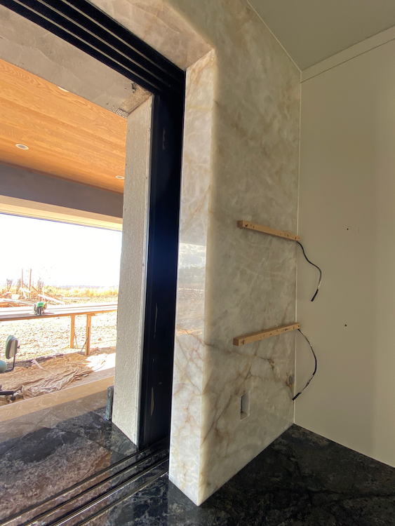 Marble-clad doorway with black frame and two light fixtures with exposed wires on the right.