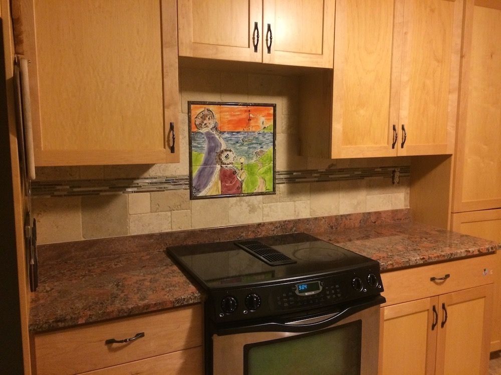 Kitchen with light wood cabinets, dark countertop, and a stovetop.