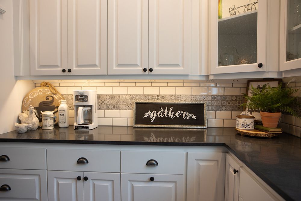 White kitchen with black countertops, subway tile backsplash, and cabinets.
