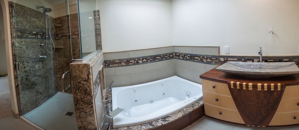 Bathroom with a jacuzzi tub, a shower, and a decorative sink on a wooden vanity.
