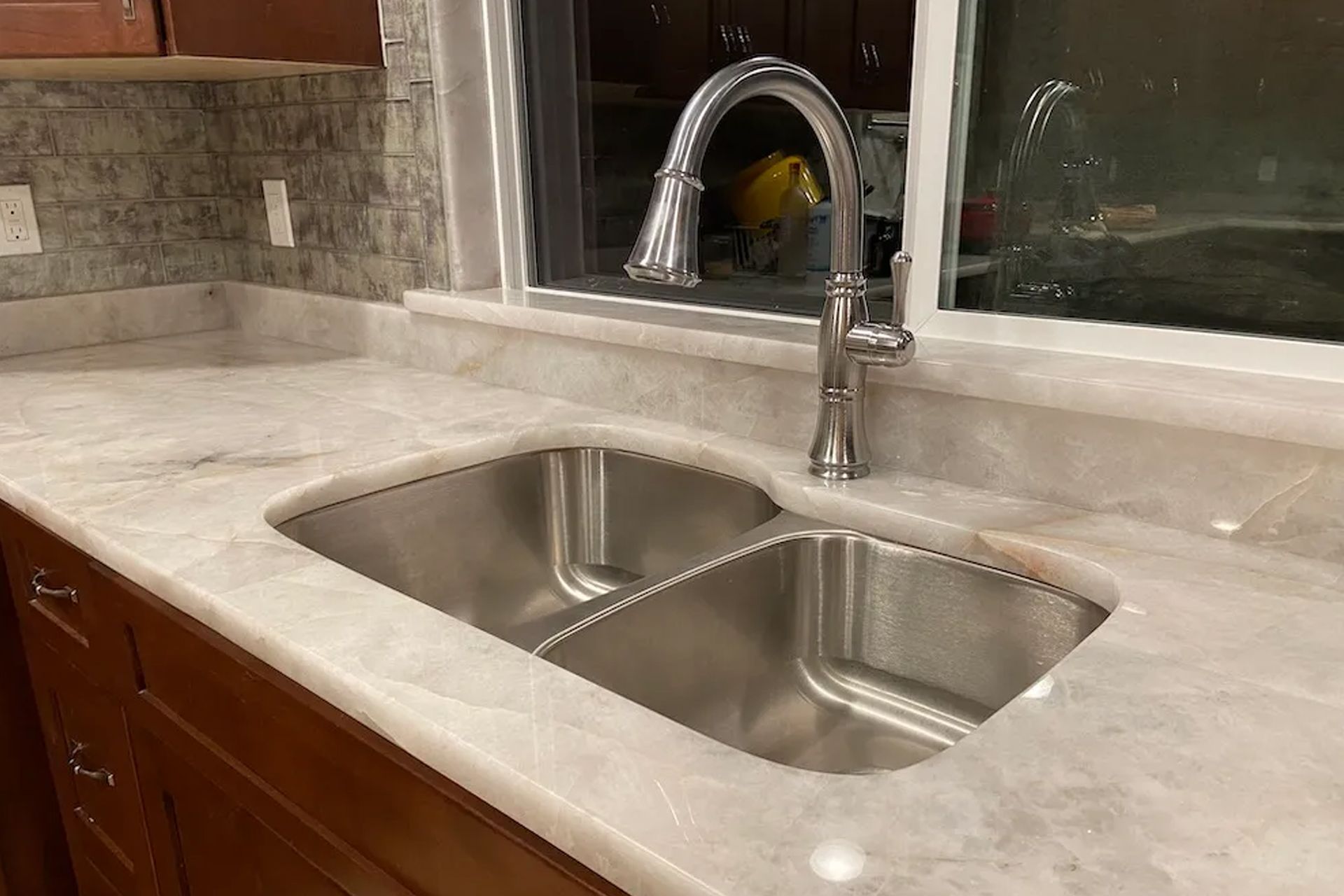 Stainless steel double sink in a kitchen with a chrome faucet.