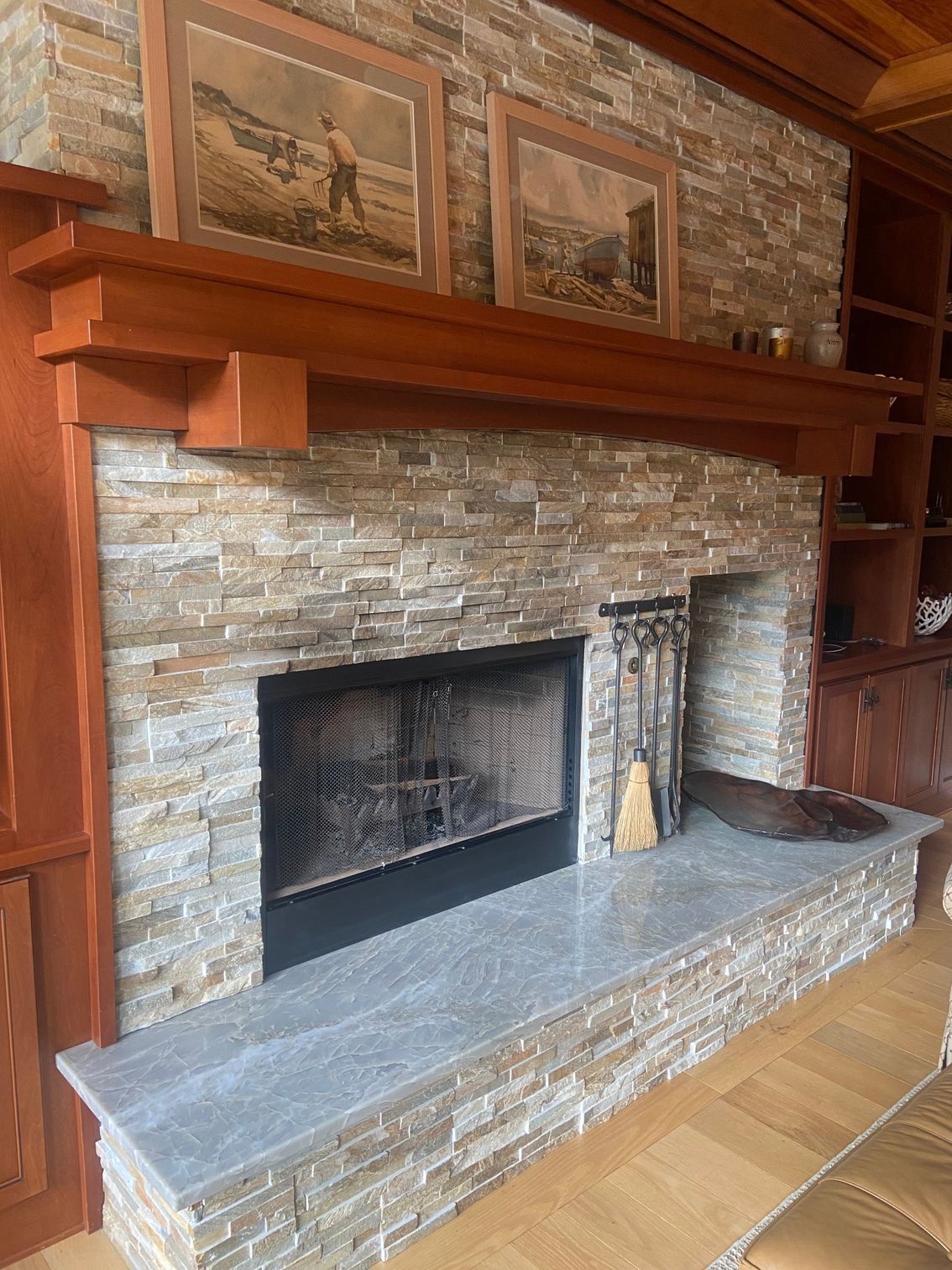 Fireplace with stacked stone surround, wood mantel, and stone hearth. Artwork hangs above.