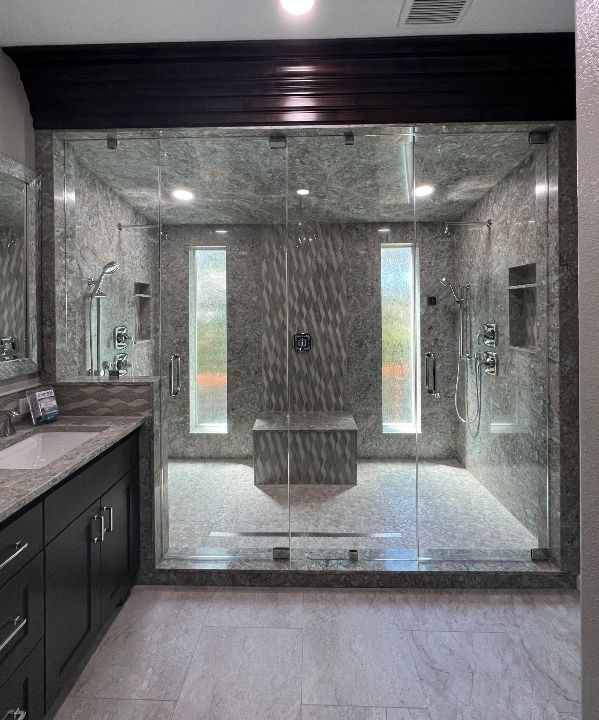 Spacious bathroom with glass shower, stone walls, and dark wood accents.