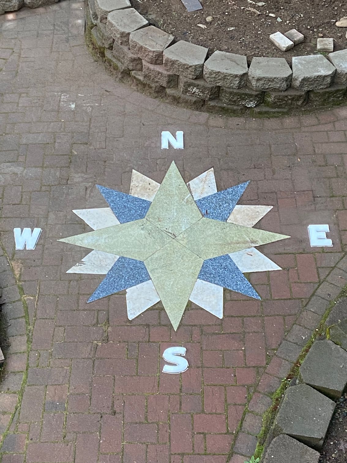 Compass rose design inlaid on brick paving, with