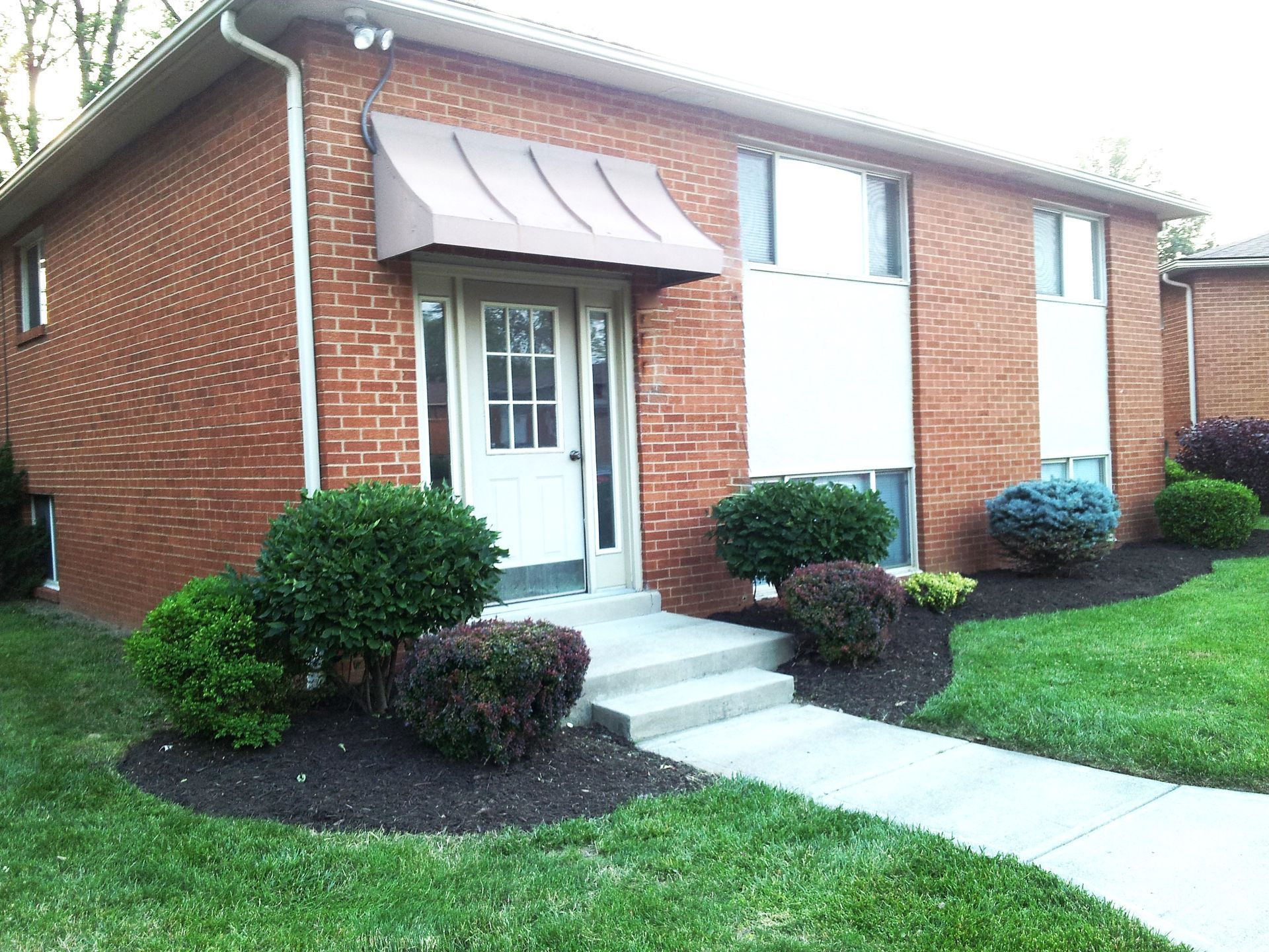 A brick house with a white door and awning