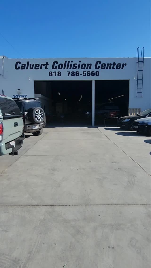 Calvert Collision Center building with open bay doors; several vehicles parked outside.