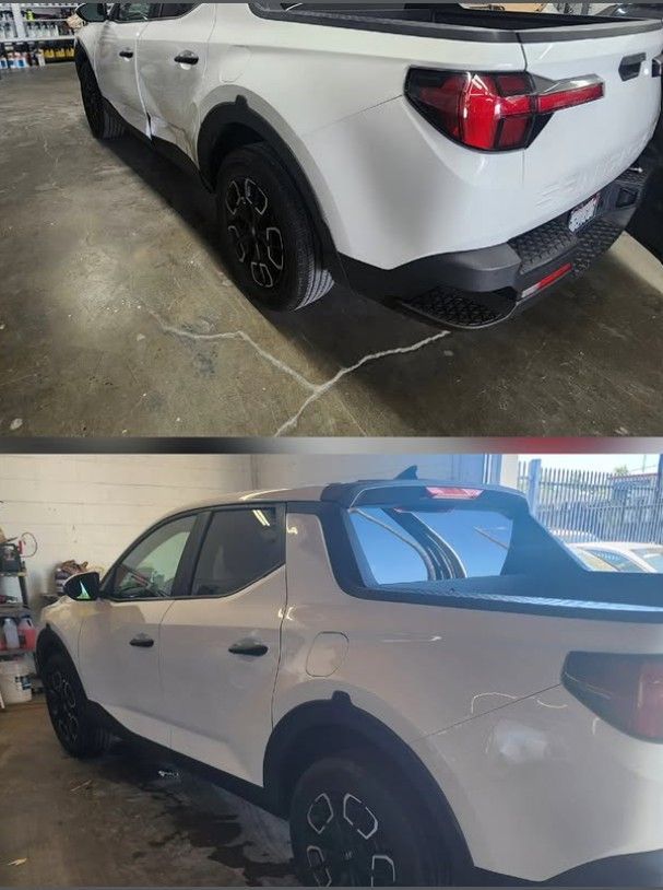 White Hyundai Santa Cruz pickup truck, damaged on side, in a repair shop.