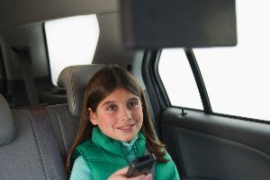 Girl with TV remote control in the car